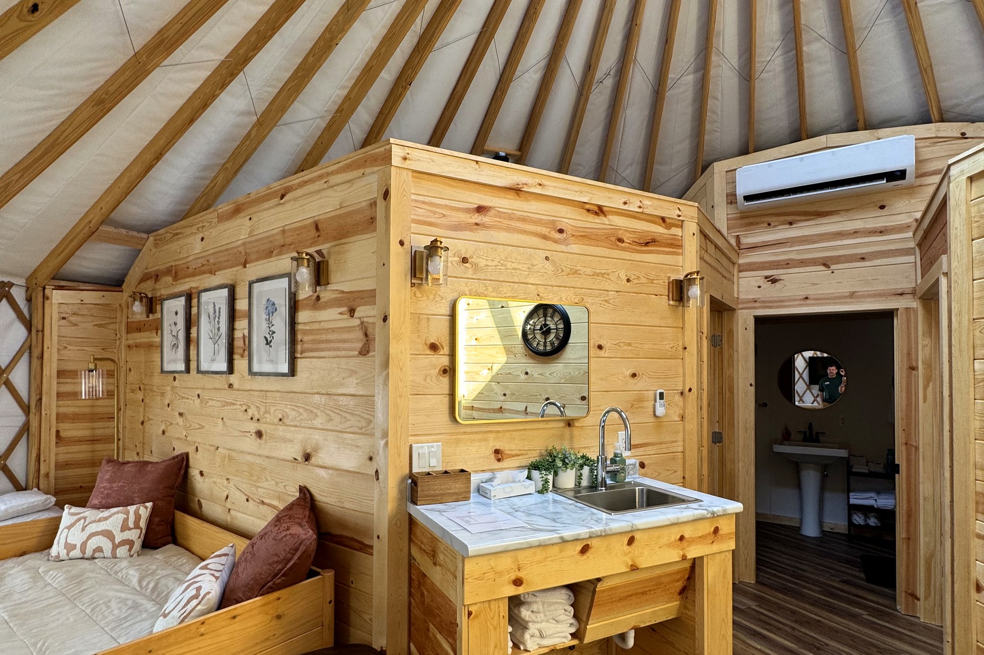 Interior of a furnished glamping yurt with bed, seating and wood floor at Haven Hills