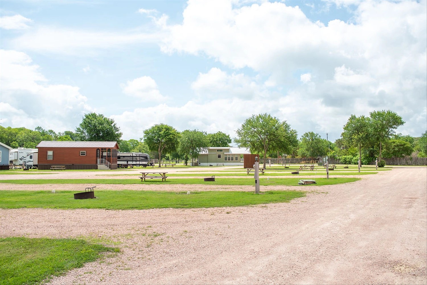 Wide view of gravel RV sites, roads and cabins laid out among shade trees at a Yogi Bear's Jellystone Park camp-resort